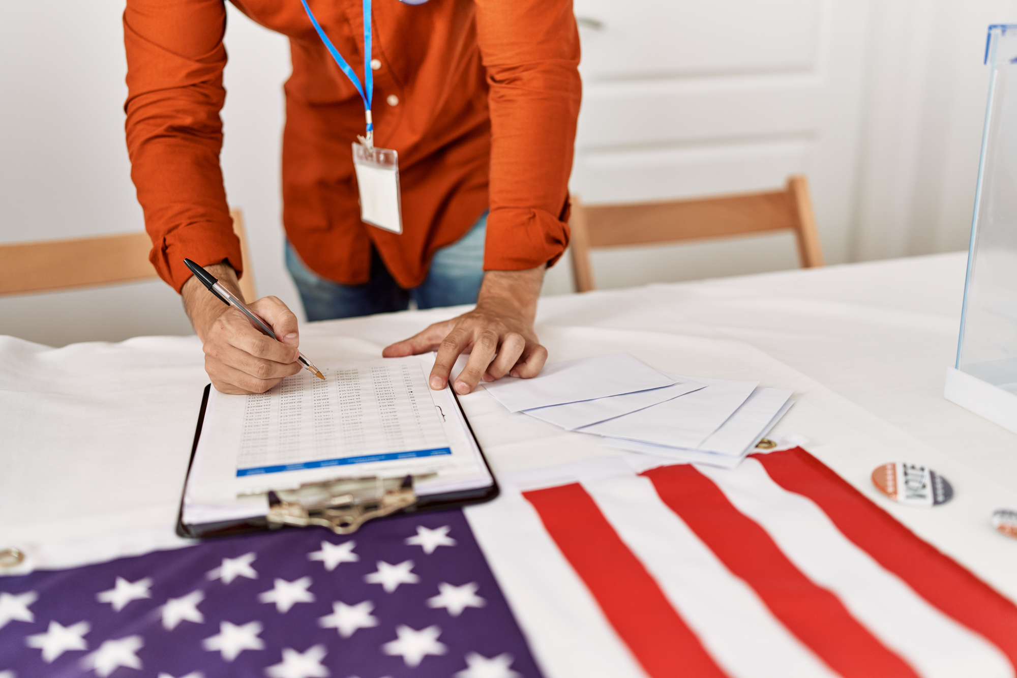 Young hispanic man writing on checklist at electoral college